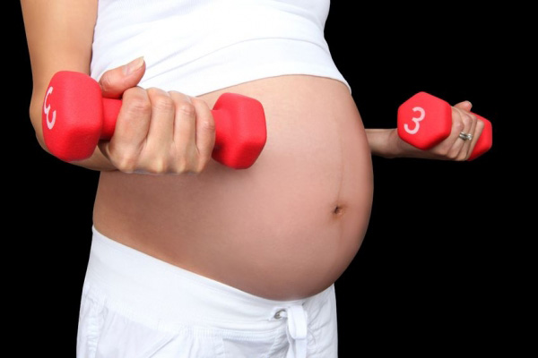 Femme enceinte s'entraîne avec des altères